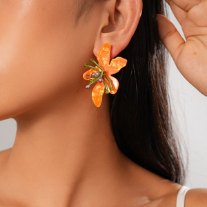Detail of orange resin flower earring with green stem and beads on model ear
