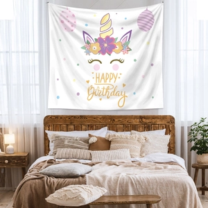 Detailed view of white unicorn happy birthday tapestry hanging in a cozy bedroom setting