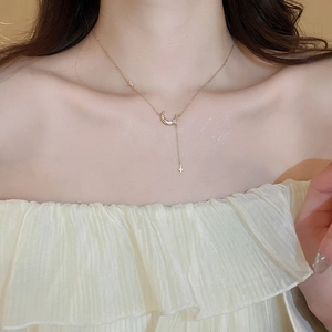 Détail macro d'un collier en Y doré avec un croissant de lune en zircon et pendentif étoile
