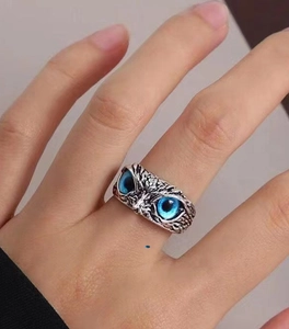 Close-up of vintage owl ring with blue eyes and silver finish on person's finger