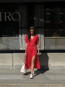 Detail of red polka dot V-neck dress featuring short puff sleeves and a stylish front slit