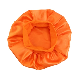 Detail showing bright orange satin hair bonnet with wide elastic band and silky texture