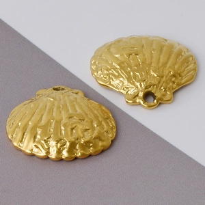 Détails macro de deux breloques coquillages dorés texturés pour la création de bijoux DIY