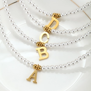 Detailed macro view of four elegant pearl necklaces with gold initial pendants A B C D