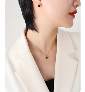 Detail of heart-shaped black zircon earrings and necklace set with gold plating
