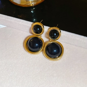 Close-up of vintage resin round drop earrings with black inlay on pink velvet box
