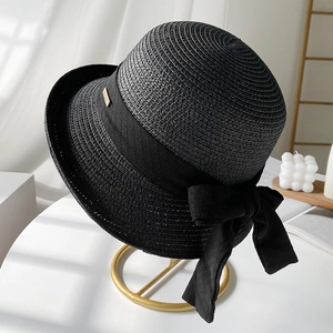 Chapeau de soleil élégant en paille tressée noire avec grand nœud sur support doré