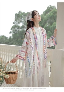 Dettaglio del cardigan traforato bianco con motivi geometrici colorati e bordi con frange
