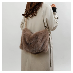 Detail of brown plush tote bag with V-shaped texture and metal chain strap on model