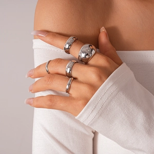 Detailed view of five-piece silver polished geometric ring set on model's hand