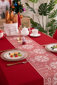 Christmas table runner with red reindeer patterns and tassels in a festive setting
