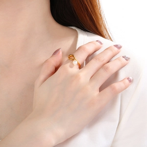 Elegant gold knot ring with white pearl on hand, minimalist stainless steel jewelry