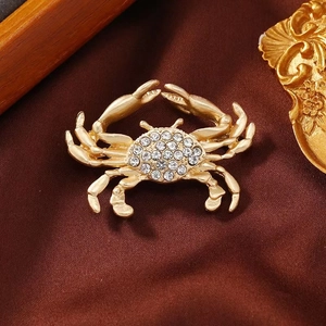 Vintage golden crab brooch with white rhinestones on brown velvet background
