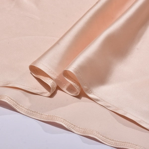 Gros plan sur le tissu en satin rose montrant la texture soie et l'ourlet roulé