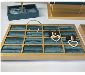 Détail d'un plateau bijoux 16 compartiments en velours vert foncé avec cadre doré chic