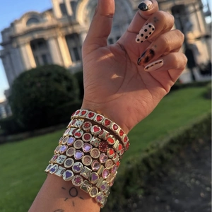 Bracelets hip hop dorés superposés avec breloques cœurs colorés et détails cerise
