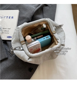 Detail showing the spacious interior of a pleated light grey bucket bag with daily items