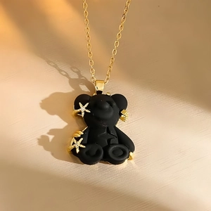 Detail of a matte black resin bear pendant with gold star accent on a dainty gold chain