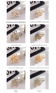 Macro detail of acetate flower hair claws in iridescent white, grey and orange colors