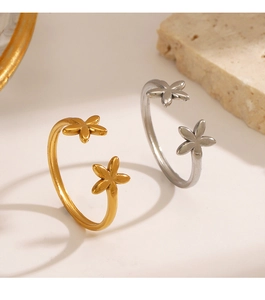 Detailed close-up of 18K gold and silver floral rings on a minimalist stone background