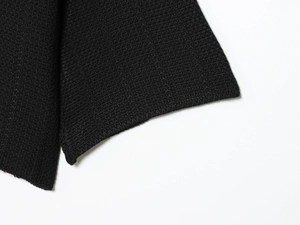 Macro detail of the high-quality black knitted fabric texture with clean edge binding