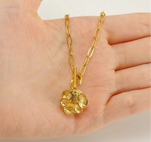 Dettaglio della collana con ciondolo a fiore, chiusura a levetta OT e catena a maglie oro