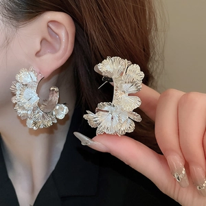 Boucles d'oreilles créoles C en forme de fleurs argentées avec finition métallique