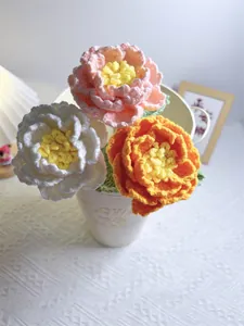Close-up of pink, white, and orange handmade crochet flowers in a ceramic pot