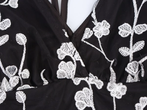 Détail de broderie florale 3D blanche sur tulle noir transparent de robe col en V