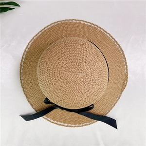 Summer straw sun hat with black ribbon bow and scalloped lace edge for beach