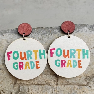 Detail shot of wooden circle earrings with colorful FOURTH GRADE text on stone background
