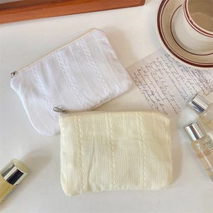 Detail of quilted cotton makeup bags with vertical lace embroidery and metal zippers
