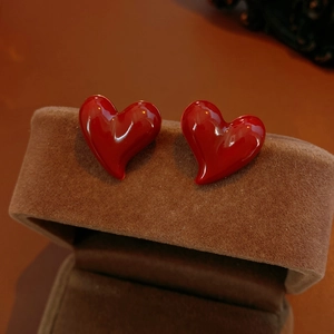 Close-up of red heart stud earrings in shiny glaze finish on brown velvet jewelry box