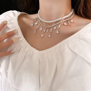 Gros plan d'un collier double épaisseur avec perles blanches et pompon en zircon étincelant