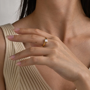 Detail of adjustable gold ring with square clear zircon on model's hand with warm lighting