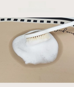 Close-up of cleaning a cream absorbent leather mat with soap foam and a long brush