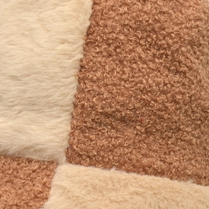 Gros plan des coutures contrastées entre fausse fourrure blanche et laine d'agneau camel