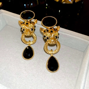 Macro view of gold cheetah earrings with black gemstones and sparkling crystal accents