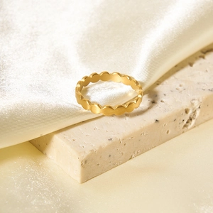 Macro detail of wave textured 18K gold plated stainless steel ring on marble surface