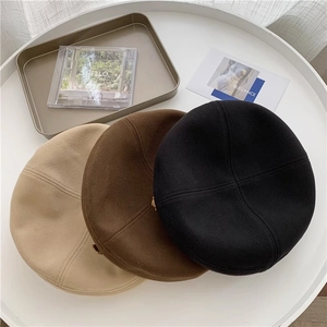 Detailed overhead view of knitted wool beret hats in beige, coffee, and black tones