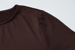 Détail de l'encolure ronde et des coutures d'épaule sur robe plissée marron chocolat