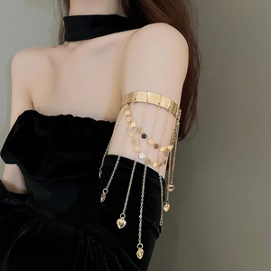 Detail of gold arm cuff featuring multi-layer chain tassels and solid heart pendants