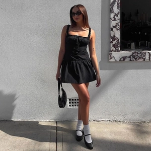 Close-up of black spaghetti strap dress featuring a square neck and drawstring pleat detail