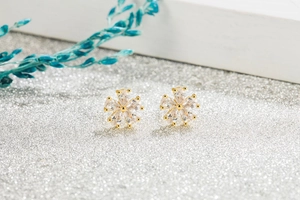Macro shot of elegant six-petal flower stud earrings with clear zircon stones and gold plating
