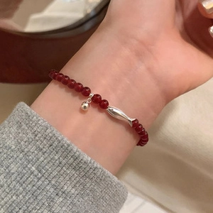 Close-up of a s925 silver beaded bracelet featuring red beads and a small fish charm