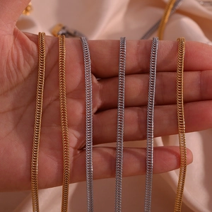 Detail of 3mm gold and silver foxtail chains held by hand over pink satin