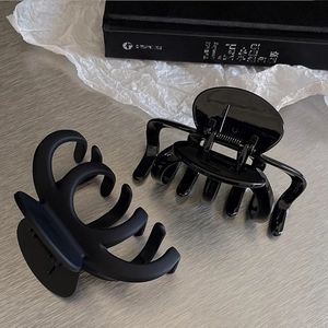 Detail of large black hair claw clips in matte and glossy finishes for women
