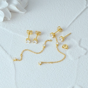 Macro detail of 925 silver gold-plated stud earrings with zircon stones and long chain