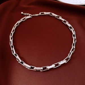 Close-up of polished silver alloy chain necklace links on deep burgundy velvet background