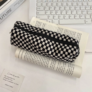 Close-up of checkerboard velvet pouch with high-quality metal zipper on a desk